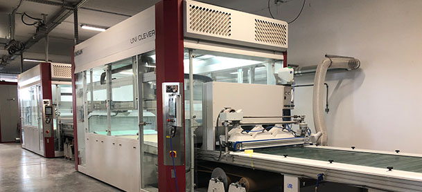 A machine in a factory painting wooden boards to be used on boats