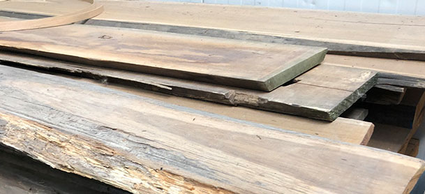 Wooden boards resting in a pile, waiting to be polished and used to build a boat