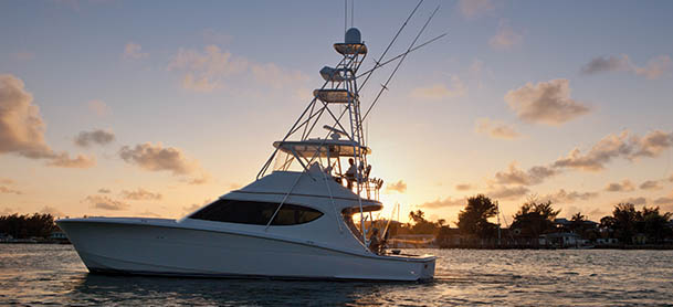 A Hatteras yacht idle in open water with the sun setting behind it
