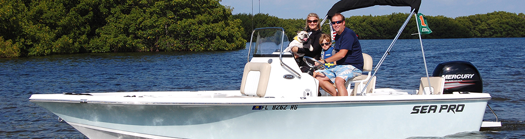 male, female, and child with dog riding in a light blue fishing boat