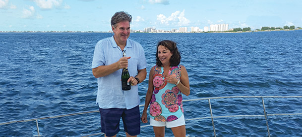 couple opening champagne on a boat