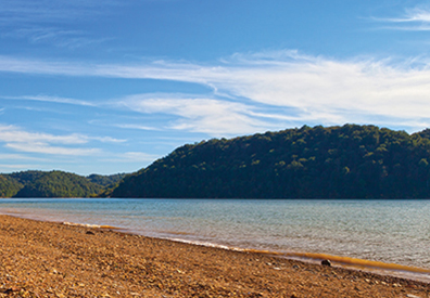 clay sand on the shore with large mountain in the background