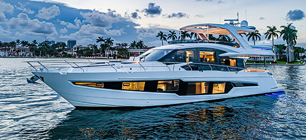 A Galeon 680 Fly resting in open water at sundown with the interior lights on