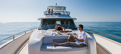 A Male and Female lounging on a sunpad on the bow of a yacht