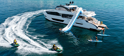 Yacht in the water with waterslide with people in the water and on jet skis