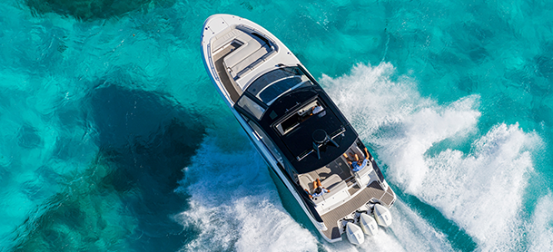 A boat with a white motor speeds through the water, creating splashes as it moves swiftly across the surface.