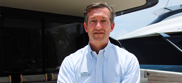 Randy Coleman stands outdoors, in front of a yacht and building.