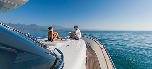 A man and woman sit on the front of a yacht