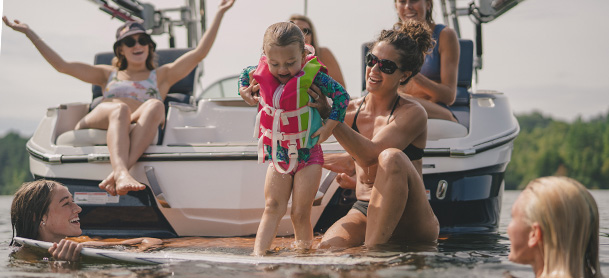 Family on boat with kids jumping in water