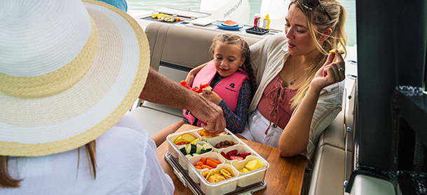 A man serves food from a tray filled with vegetables and fruits.