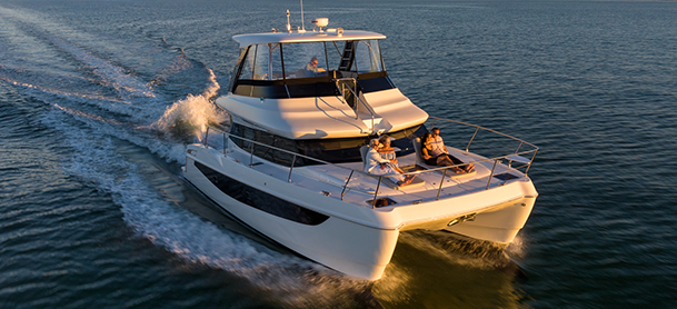 A luxury catamaran sails smoothly on calm waters at sunset.