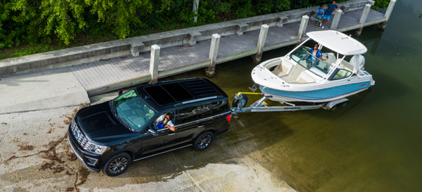 A white boat is pulled from the water by a towing car