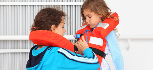 A child has help tying their life jacket