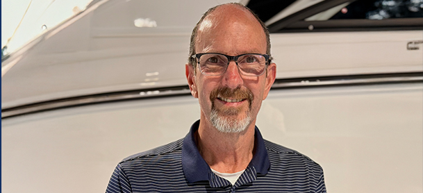 The new GM of MarineMax Danvers, Ron Baker, smiles warmly in front of a white yacht.