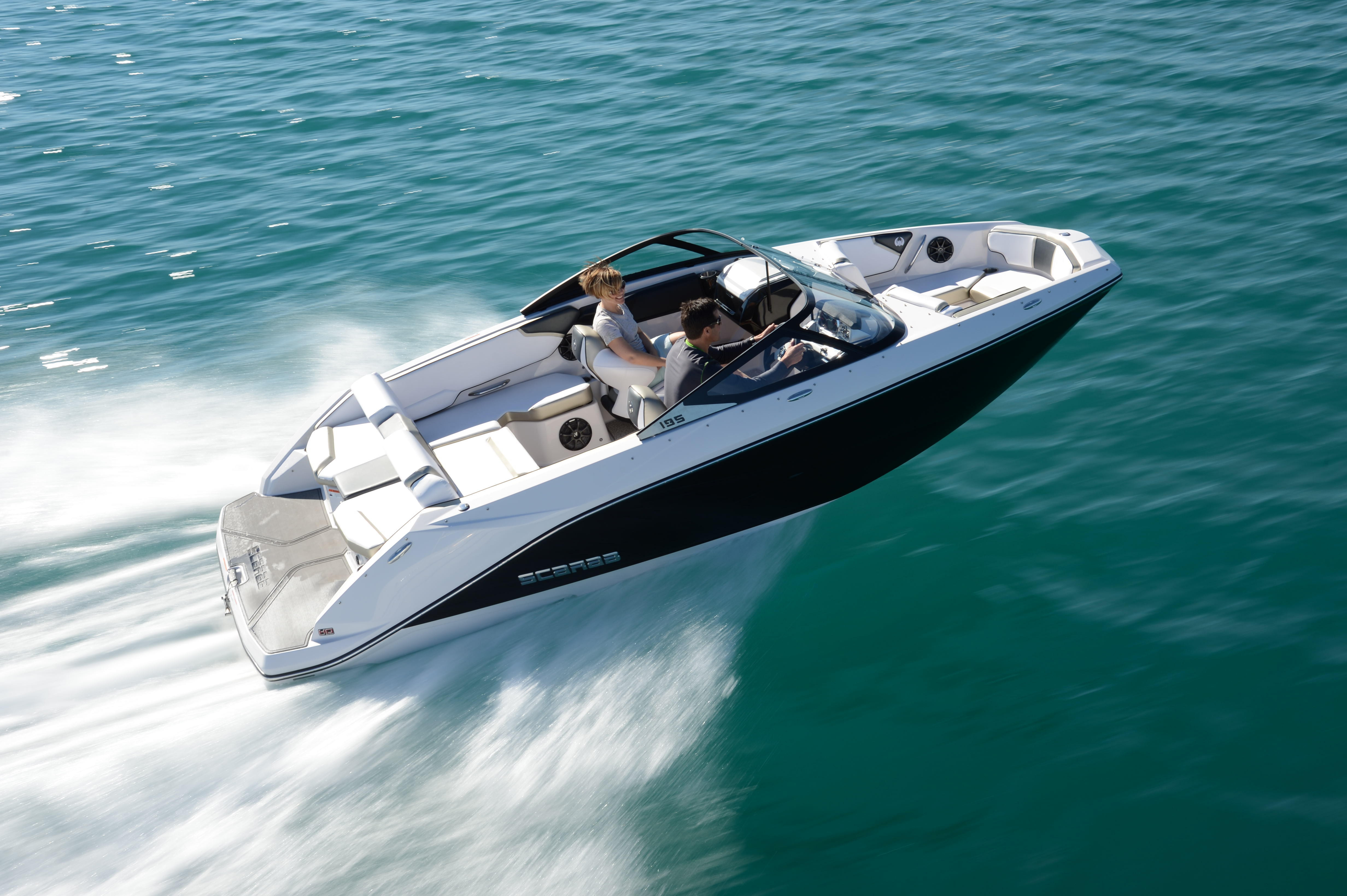 A dual console boat speeding out on the water with smiling couple