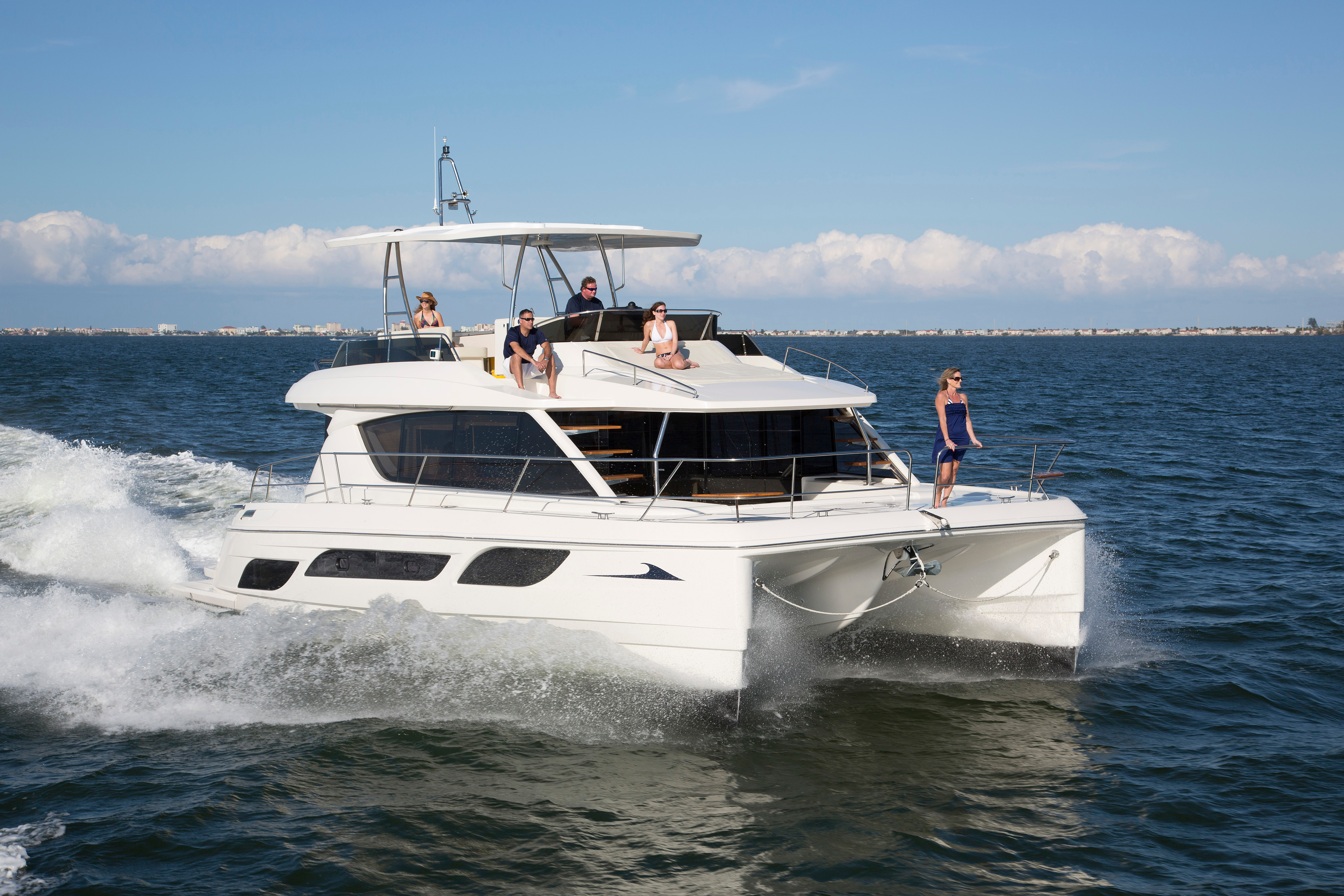 Power catamaran cruising in water with people on the deck enjoying sun