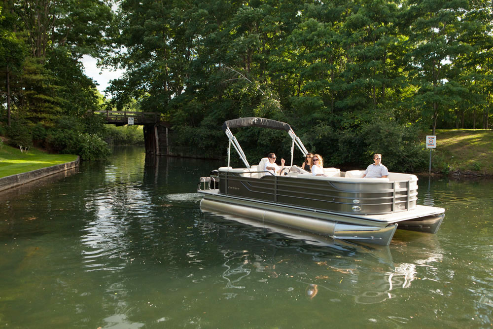Pontoon boat traveling through waterway with a group onboard