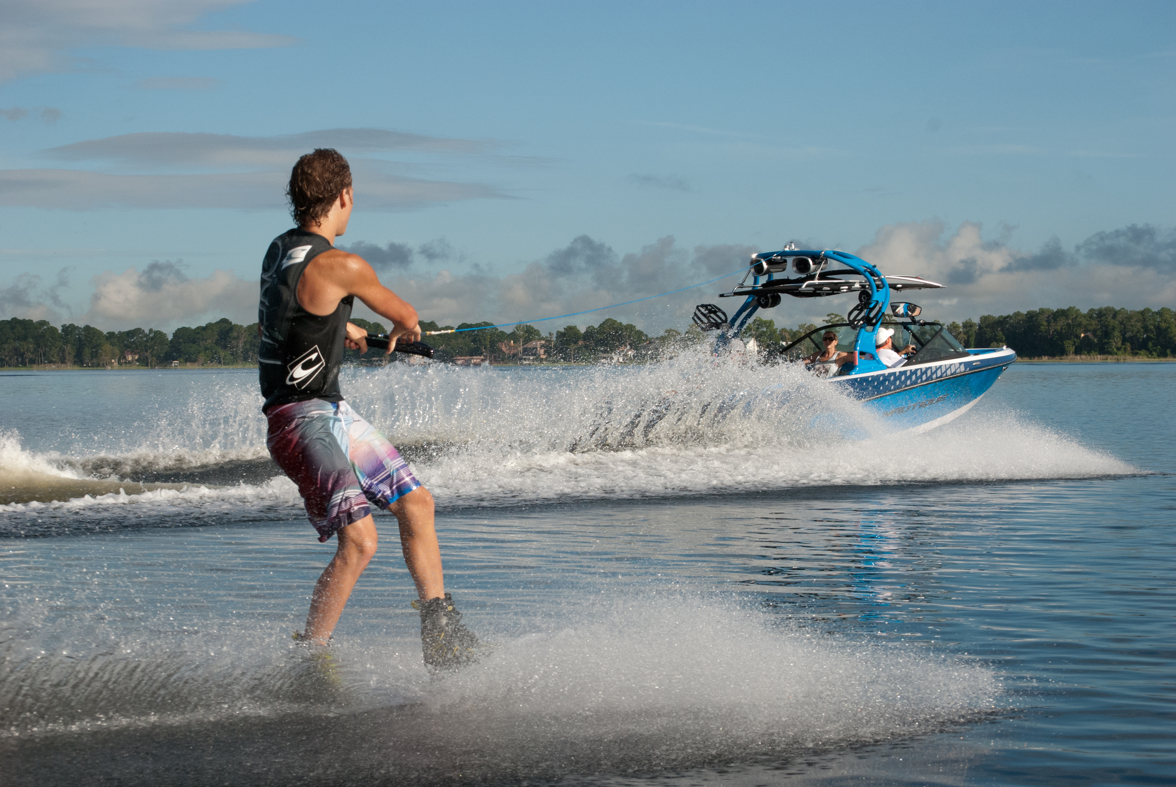 Guy on waterski being pulled by ski boat on a lake