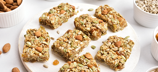 granola bars topped with a variety of nuts and seeds arranged neatly on a wooden surface