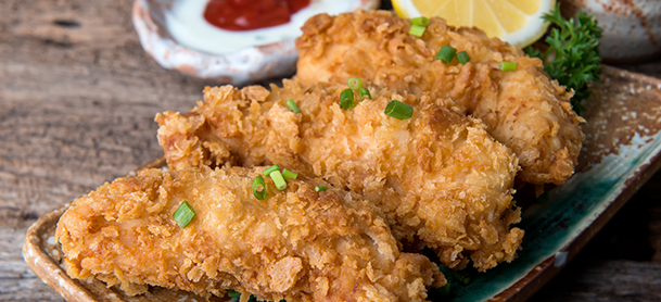 a plate of crispy fried chicken pieces garnished with herbs served on a white dish