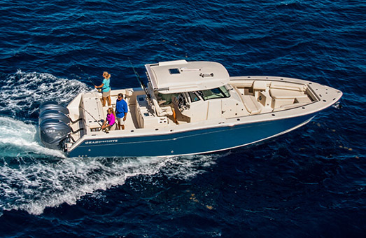 offshore fishing boat in water with people standing on the back fishing.