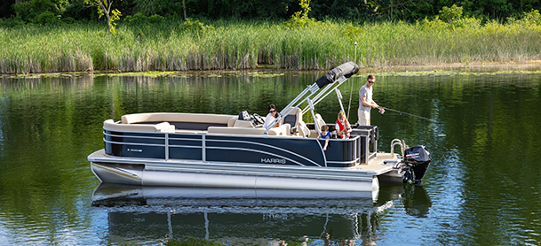 A family on a pontoon boat enjoys a serene day fishing on a calm lake, surrounded by lush greenery.