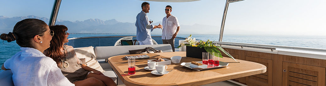 Two men and two women on the flybridge of an Azimut yacht, with drinks and crackers on the table