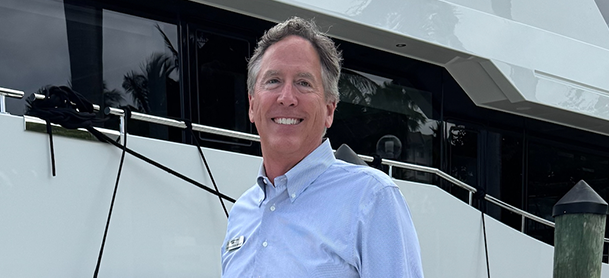 Cary Smart, Director of Motor Yachts, poses next to a boat at the dock, showcasing his passion for boating.