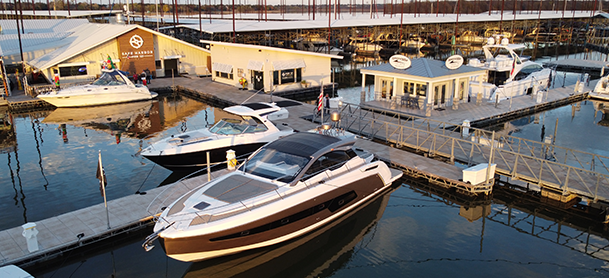 A marina with luxury boats docked near modern wooden buildings.