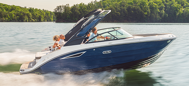 A sleek blue SDX 230 with four people aboard swiftly glides across a tranquil lake.