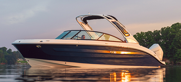 SDX 250 OB with a navy and white hull floats on calm water at sunset. 