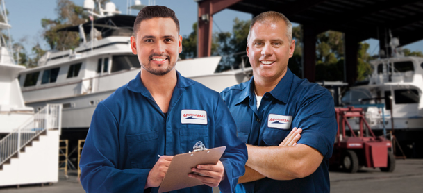 Two men with crossed arms smiling with boats behind them