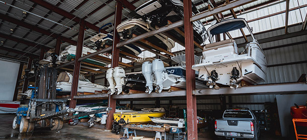 A storage rack holding several boats in three rows, with a pickup truck on the ground in front