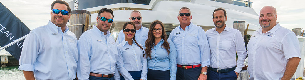 MarineMax staff posing and smiling in front of boat