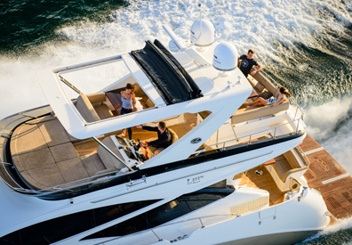 group of people relaxing on second floor of large yacht speeding across the ocean