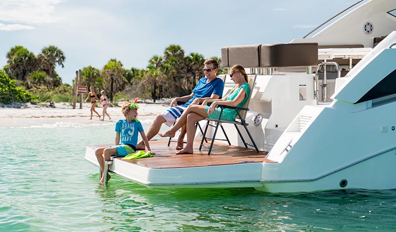 family sitting on swim platform on the aft of an anchored boat