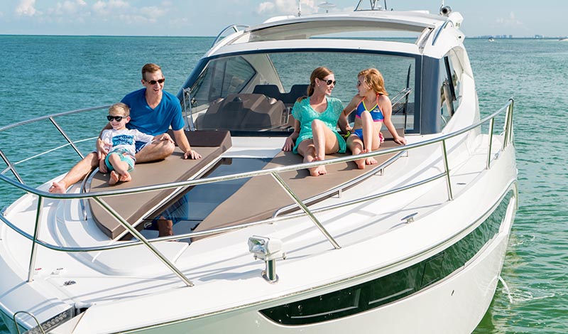 family laying on a sunpad on the bow of a boat