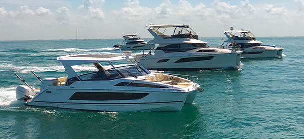A fleet of Aquila power catamarans lined up and cruising through open clear water
