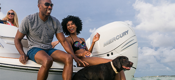Couple and dog on back of boat laughing