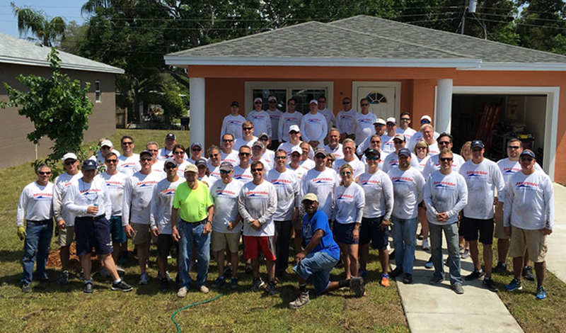 group of marinemax employees in front of habitat for humanity house