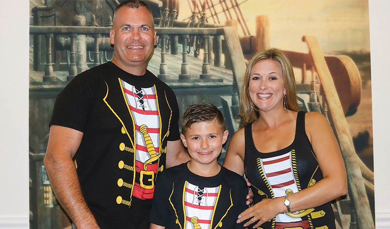 two adults in pirate shirts next to a young boy in a pirate shirt