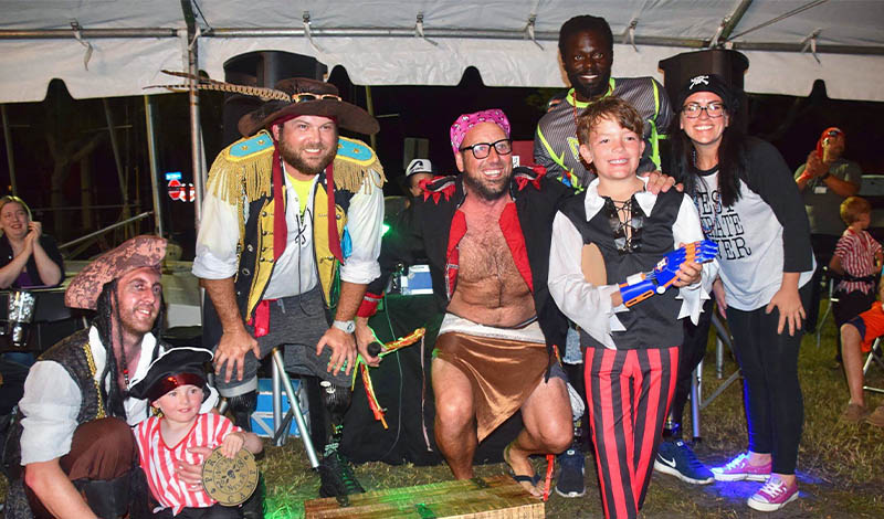 a group of adults in pirate costumes with a young boy