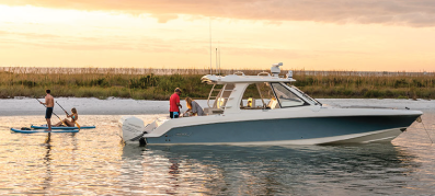 Boston Whealer Realm on the water with people paddleboarding by the boat