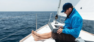 A man looking at a laptop on a boat
