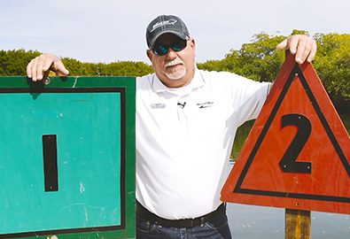 A man standing by two channel markers