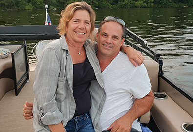 A man and woman smiling on a pontoon in the water