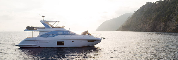 an azimut yacht resting in calm water with the sun setting behind it