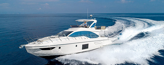 an azimut yacht with a white hull cruising through blue water from right to left