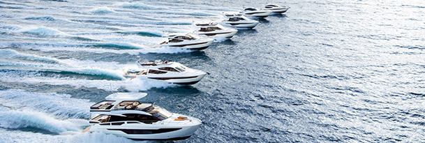 a row of galeon yachts all cruising through open blue water from left to right
