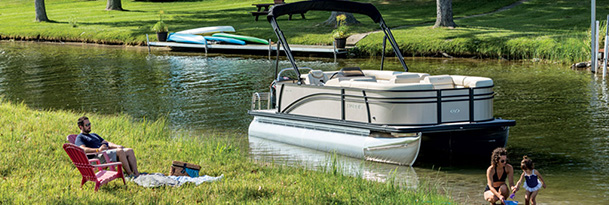 a couple and their child playing by a harris pontoon